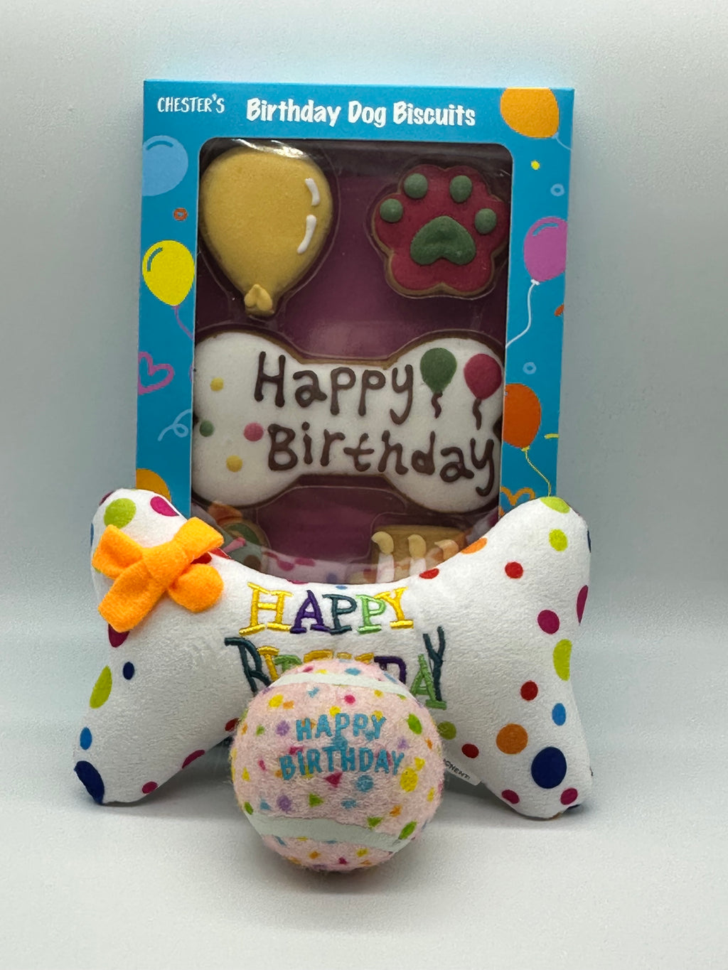 Dog birthday box with birthday biscuits, a soft squeaky bone and a ball